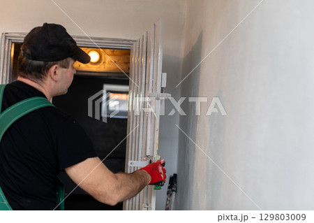 A professional worker is carefully adjusting a ladder in a space that is being renovated 129803009