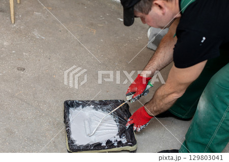 A construction worker is applying cement for repair or renovation tasks at a site 129803041