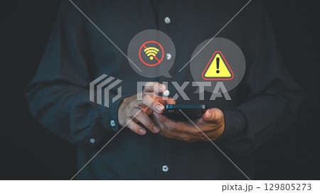 Person holding a smartphone with no Wi-Fi and warning alert icons, representing connection failure, network error, or internet outage issue. 129805273