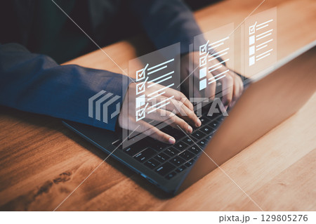 Female employee using a laptop and interacting with digital checklist. Concept represents task management, planning, productivity, and digital organization in a modern workplace. Female employee using a laptop and interacting with digital checklist. Concept represents task management, planning, productivity, and digital organization in a modern workplace. 129805276