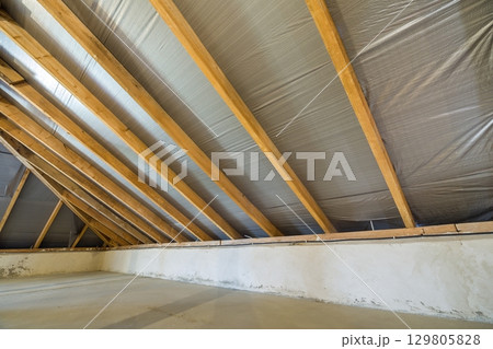 Attic of a building with wooden beams of a roof structure. Attic of a building with wooden beams of a roof structure. 129805828