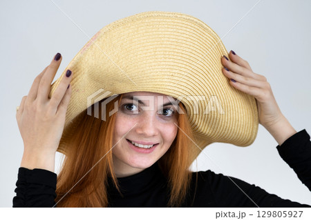 Portrait of funny redhead woman in bag yellow straw hat. Portrait of funny redhead woman in bag yellow straw hat. 129805927