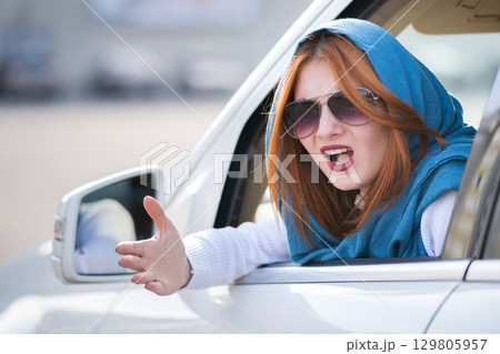 Closeup portrait of pissed off displeased angry aggressive woman driving a car shouting at someone with hand fist up. Negative human expression consept. 129805957