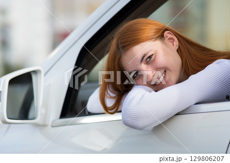 Young woman with red hair driving a car. 129806207