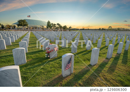 Sarasota National Cemetery with many white headstones on green grass lawn at sunset. Memorial Day concept 129806300