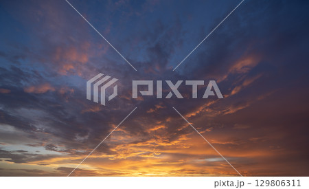 Dramatic sunset sky covered with colorful yellow clouds. Panoramic skyscape 129806311
