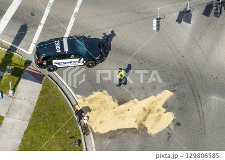 Wrecker operator workers cleaning up road surface after car crash. Sand absorbing spilled engine oil at traffic accident site Wrecker operator workers cleaning up road surface after car crash. Sand absorbing spilled engine oil at traffic accident site 129806585
