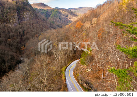 Scenic drive through Tennessee Appalachians at sunset in fall season. Car traveling on curvy forest road under vibrant autumn foliage 129806601