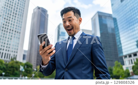 《AI画像》スマホで株取引をするビジネスマン 129808326