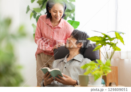 ソファに座ってくつろぐ男性と横に立つ女性 ソファに座ってくつろぐ男性と横に立つ女性 129809051