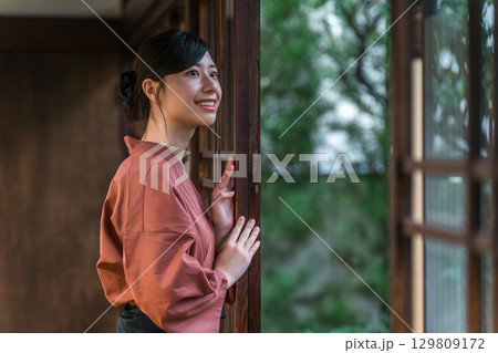 旅館の庭を眺める作務衣姿の仲居さん旅館スタッフの女性 旅館の庭を眺める作務衣姿の仲居さん旅館スタッフの女性 129809172