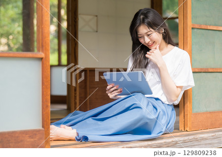 古民家でタブレットを見て笑っている若い女性 古民家でタブレットを見て笑っている若い女性 129809238
