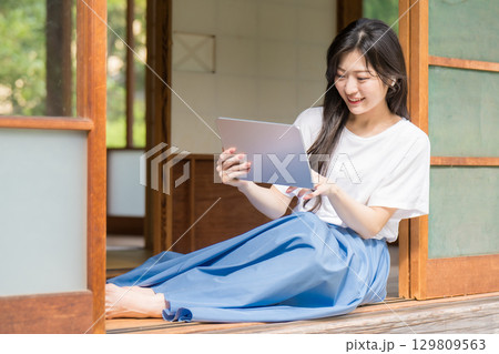 タブレット見てタッチ操作している若い女性 129809563