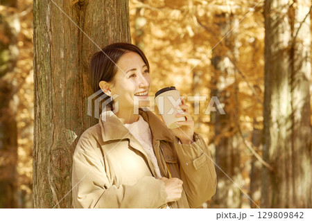 紅葉の中をコーヒーを飲む女性 ミドルエイジ 紅葉の中をコーヒーを飲む女性 ミドルエイジ 129809842