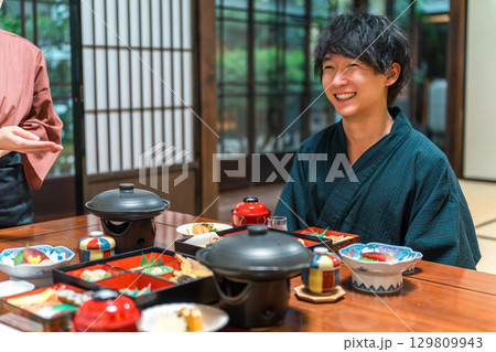 温泉旅館・旅館での食事・部屋食・夕食を食べる浴衣姿の男性 129809943