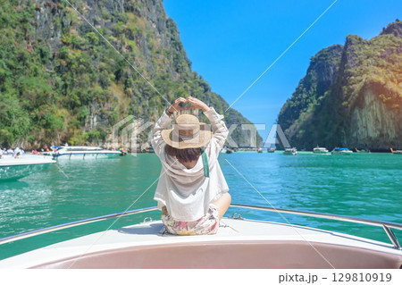 Woman tourist on boat trip, happy traveller relaxing at Pileh lagoon on Phi Phi island, Krabi, Thailand. Exotic landmark, destination Southeast Asia Travel, summer vacation and holiday concept Woman tourist on boat trip, happy traveller relaxing at Pileh lagoon on Phi Phi island, Krabi, Thailand. Exotic landmark, destination Southeast Asia Travel, summer vacation and holiday concept 129810919