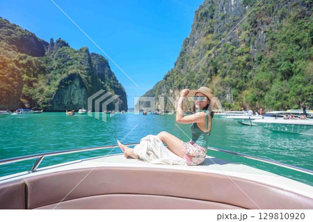 Woman tourist on boat trip, happy traveller relaxing at Pileh lagoon on Phi Phi island, Krabi, Thailand. Exotic landmark, destination Southeast Asia Travel, summer vacation and holiday concept Woman tourist on boat trip, happy traveller relaxing at Pileh lagoon on Phi Phi island, Krabi, Thailand. Exotic landmark, destination Southeast Asia Travel, summer vacation and holiday concept 129810920