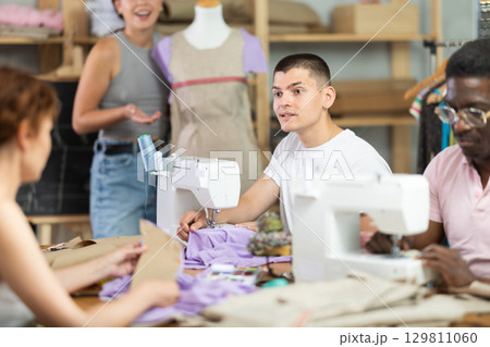 Young guy talking with woman and sewing, other working with mannequin Young guy talking with woman and sewing, other working with mannequin 129811060