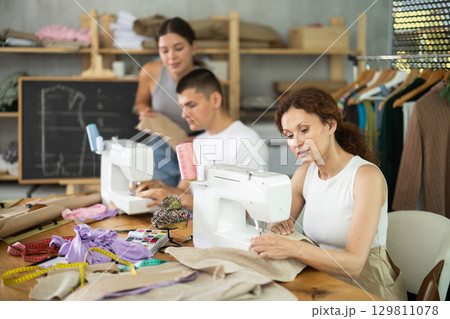 Adult woman stitching at machine during sewing class for adults 129811078