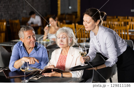 Woman waiter taking order from elderly couple in restaurant Woman waiter taking order from elderly couple in restaurant 129811186