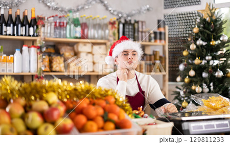 Seller sits thoughtfully near the counter 129811233