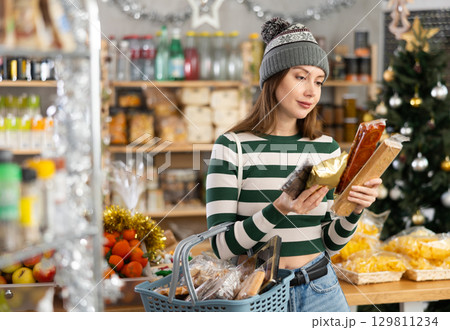While shopping on eve of New Year holidays, young lady buys sweets for festive party While shopping on eve of New Year holidays, young lady buys sweets for festive party 129811234