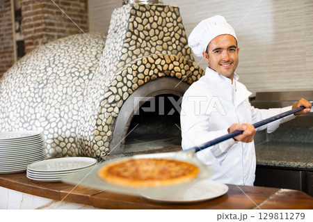 Skilled man chef preparing pizza in restaurant Skilled man chef preparing pizza in restaurant 129811279