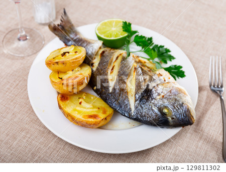 Fried dorada with baked jacket potato, lime and greens Fried dorada with baked jacket potato, lime and greens 129811302