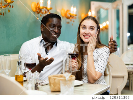Loving positive smiling pair enjoying evening meal and conversation at cozy restaurant 129811395