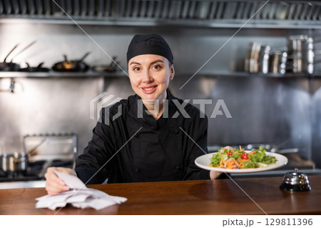 Chef checking orders and giving out salad 129811396