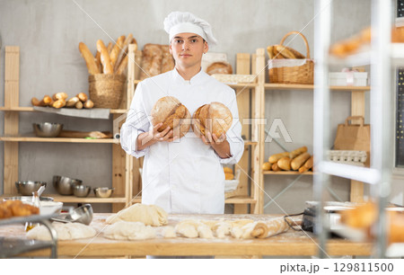 Bakery male employee holds ready made bread of bread in hands 129811500