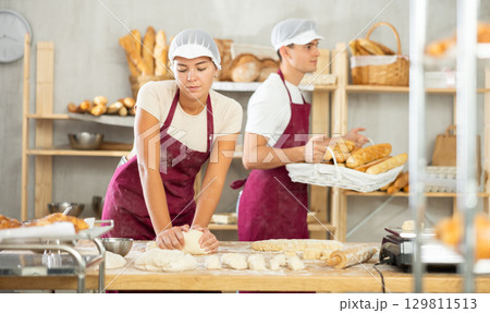 Young woman works in bakery as baker, kneads and prepare dough, works with flour. Young woman works in bakery as baker, kneads and prepare dough, works with flour. 129811513