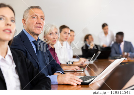 Middle aged man attending conference in meeting room Middle aged man attending conference in meeting room 129811542