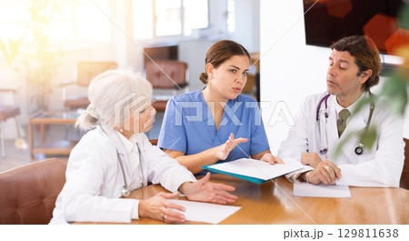 Young female physician discussing diagnosis of patients with colleagues 129811638