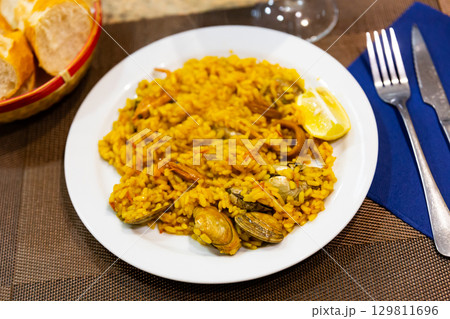 Portion of freshly prepared crumbly paella with seafood, supplemented with lemon Portion of freshly prepared crumbly paella with seafood, supplemented with lemon 129811696