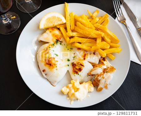 fried cuttlefish drizzled with white garlic and parsley sauce,lemon wedge and french fries on plate fried cuttlefish drizzled with white garlic and parsley sauce,lemon wedge and french fries on plate 129811731