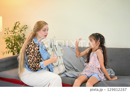 Upset little girl raising her hand in refusal while mother tries to convince her about school 129812287
