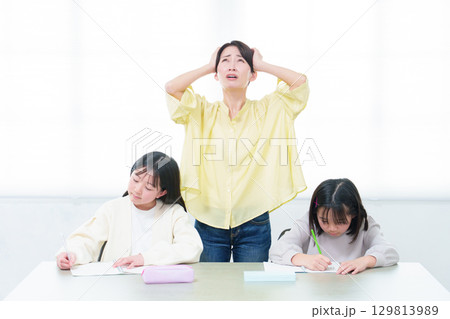 勉強をする女の子　頭を抑えるお母さん 129813989