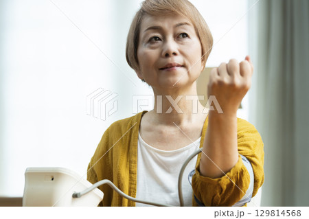 リビングで血圧を測定するシニア女性 129814568