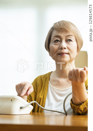 リビングで血圧を測定するシニア女性 129814573