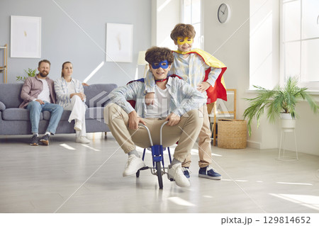 Happy playful family, parents and excited funny little brothers at home wearing super hero fancy  129814652