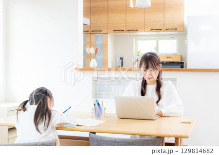 リビングで勉強をする小学生の女の子とテレワークのママ リビングで勉強をする小学生の女の子とテレワークのママ 129814682
