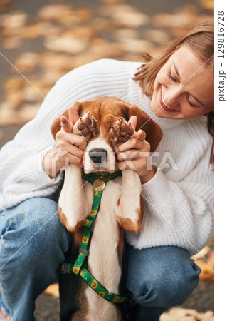 Covering the eyes with paws. Young woman is with her dog in the park Covering the eyes with paws. Young woman is with her dog in the park 129816728