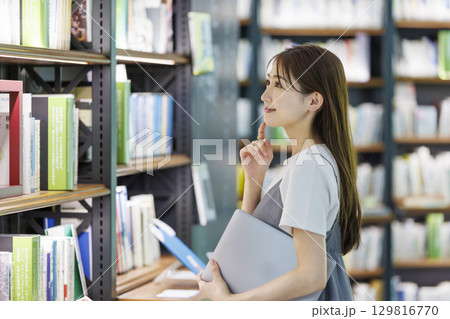図書館で本を探す若い女性 129816770
