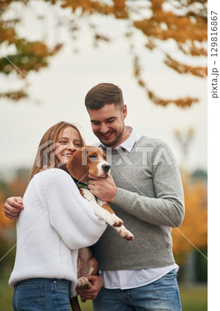 Smiling, having fun. Lovely couple are with their cute dog outdoors Smiling, having fun. Lovely couple are with their cute dog outdoors 129816867