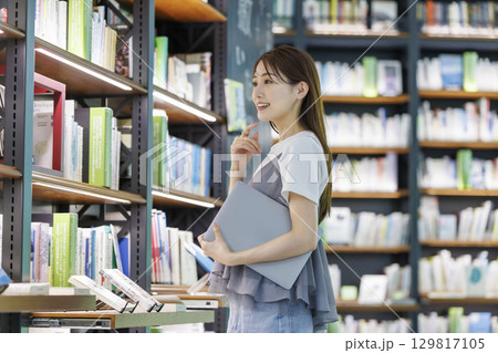 図書館で本を探す若い女性 129817105