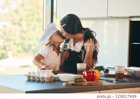Eggs and pepper. Mother with her daughter are preparing food on the kitchen 129817489
