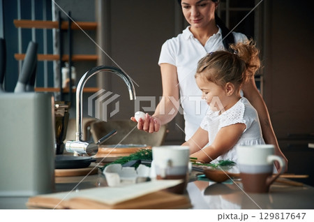 Process of learning. Mother with her daughter are preparing food on the kitchen Process of learning. Mother with her daughter are preparing food on the kitchen 129817647