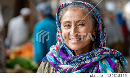 Elderly caucasian woman smiling in colorful headscarf at local market. 129818536