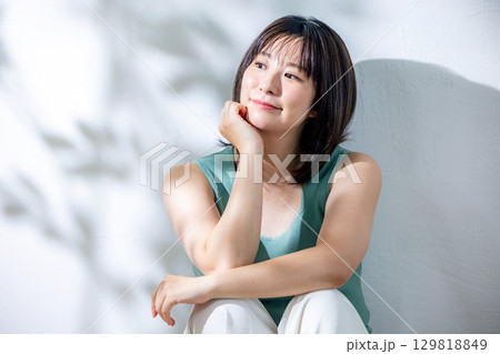 夏の日差し　壁にもたれる女性 129818849